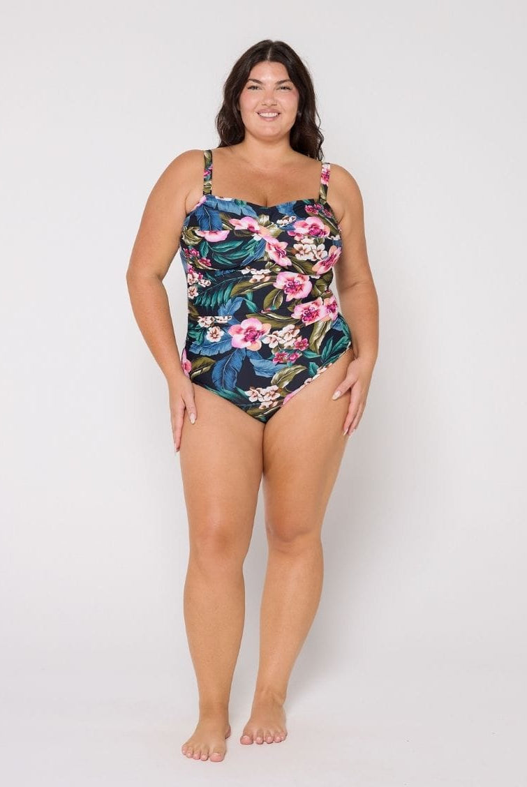 Woman in studio wearing a floral swimsuit on a white background
