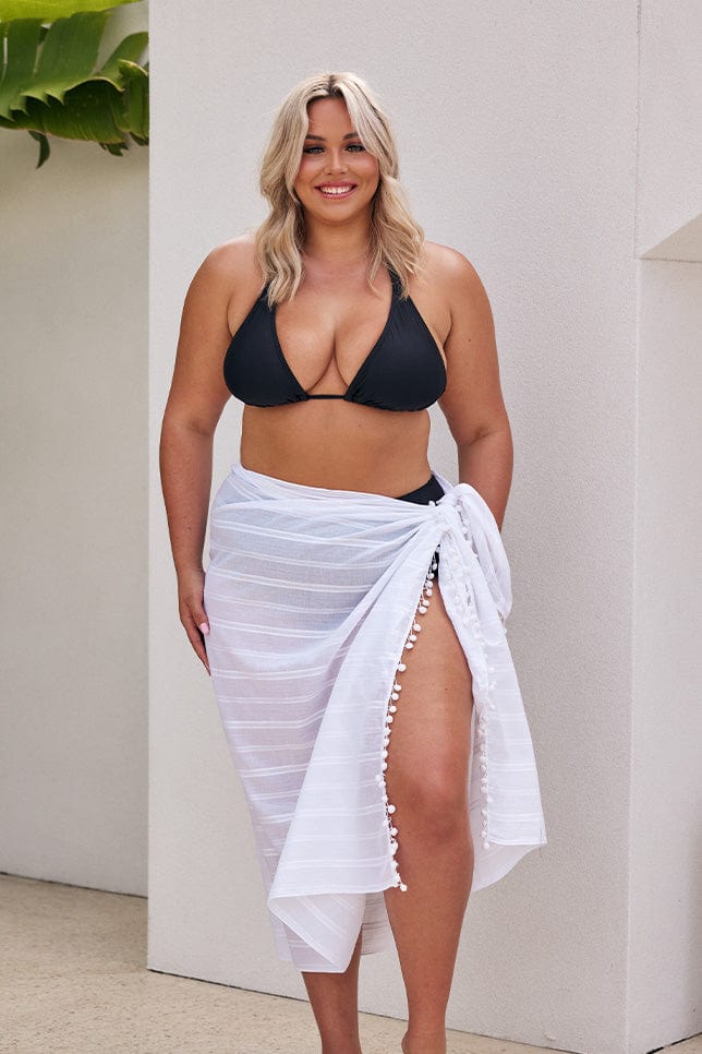 Blonde model wearing white long sarong over black bikini