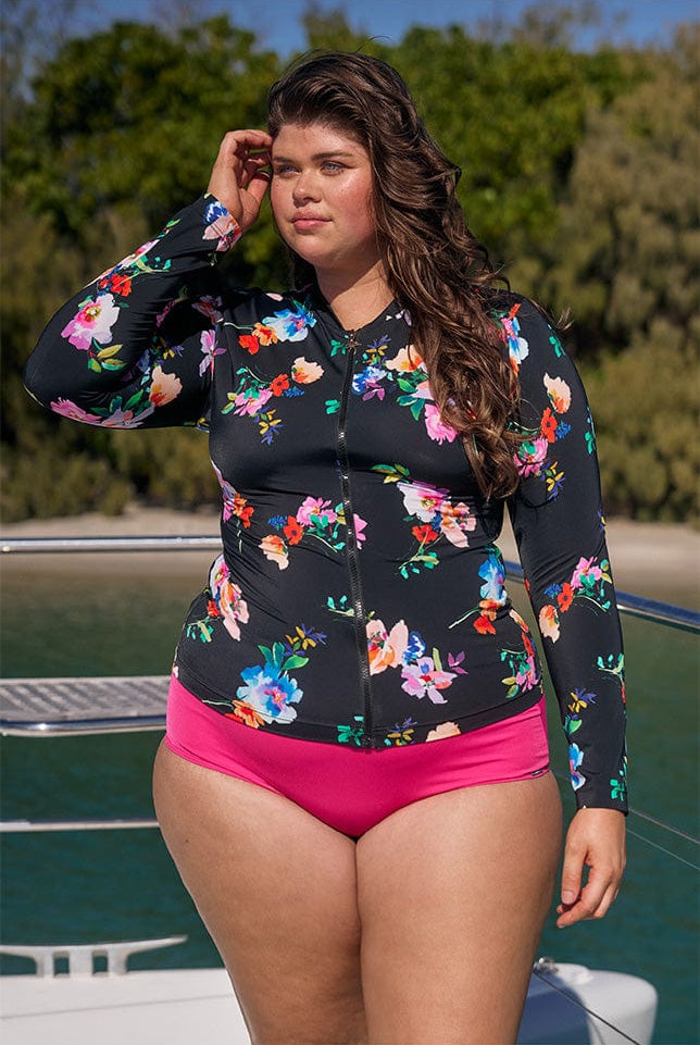 Model wearing black floral long sleeve rash vest on boat