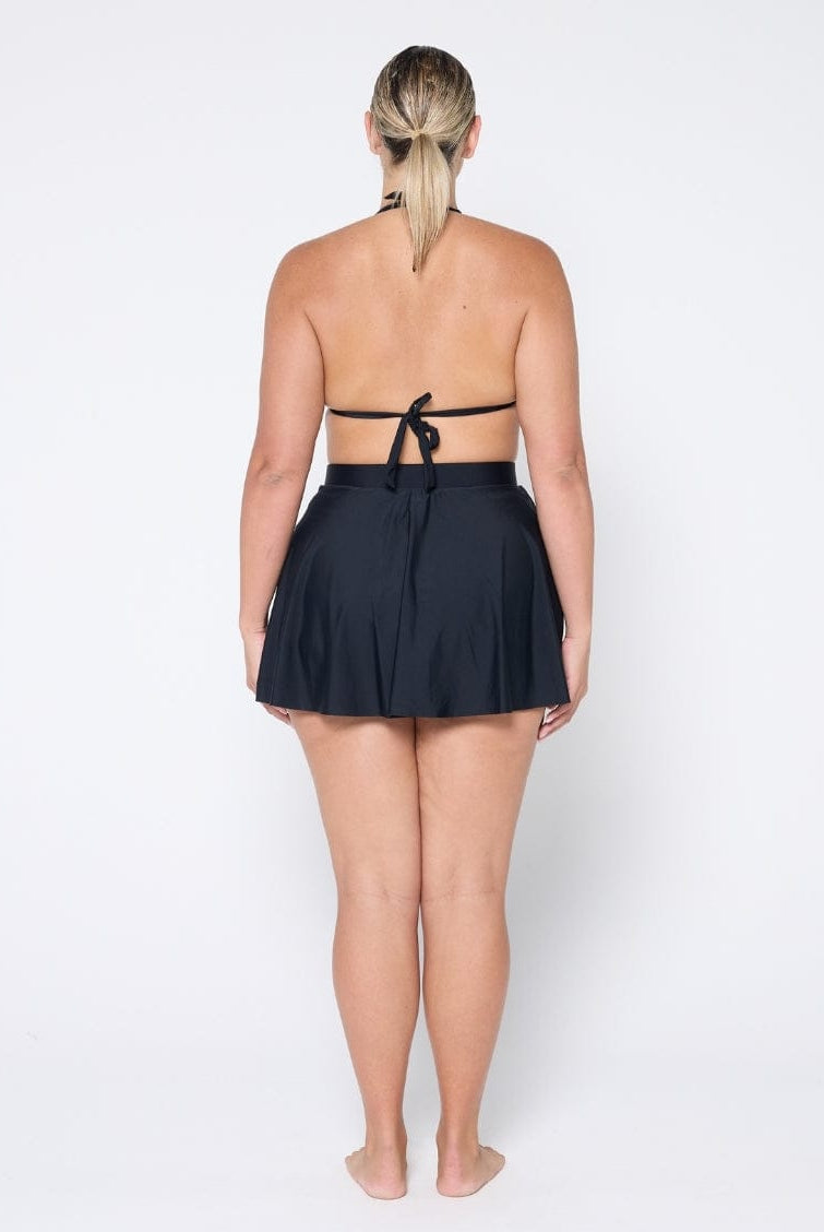 Person wearing a black halter top and skirt set on a white background