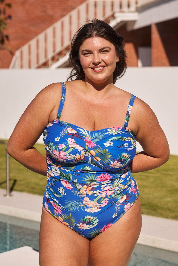 Brunette model shows supportive bandeau one piece with removable straps in blue floral print
