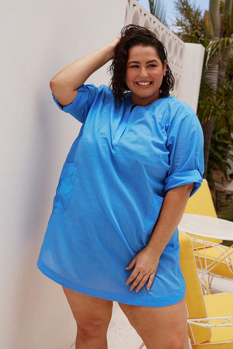 brunette model wears light blue over shirt with roll up sleeves