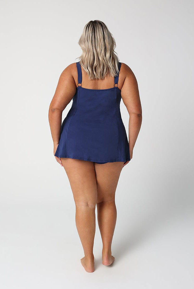 Person wearing a navy blue slip dress on a white background