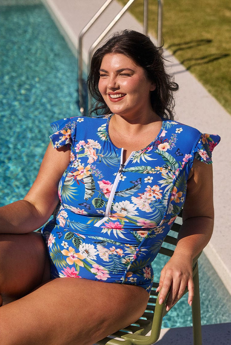Brunette model wears blue floral ruched one piece with flattering side panels and frill sleeves