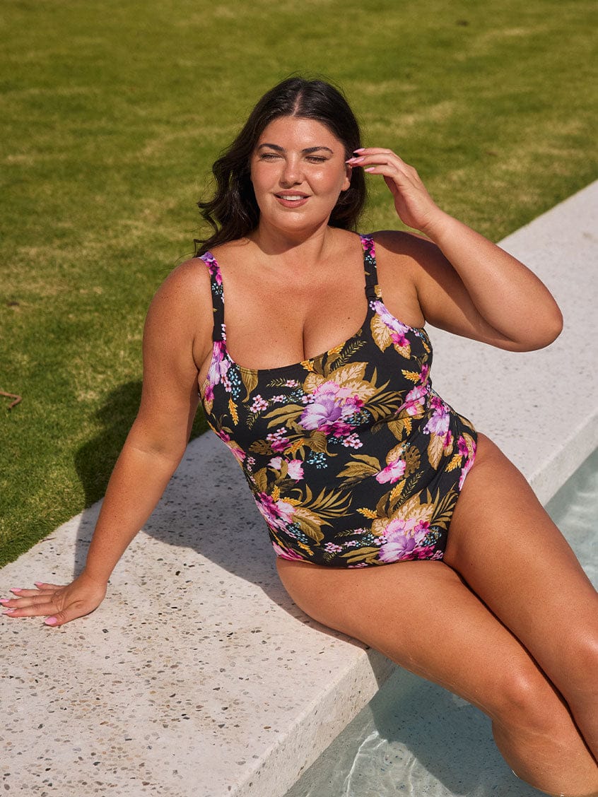 Brunette model wears flattering scoop neck chlorine resistant one piece in pink and gold florals