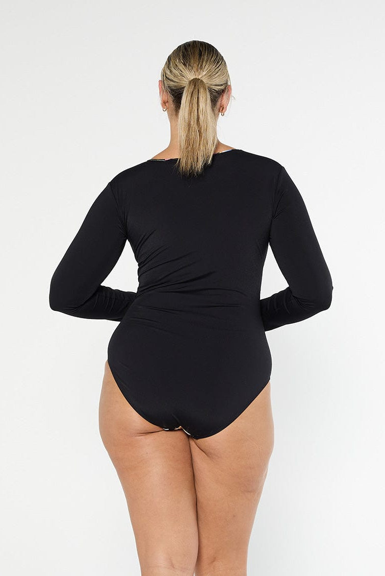 Blonde model shows the back of black chlorine resistant long sleeve one piece with full coverage bottom