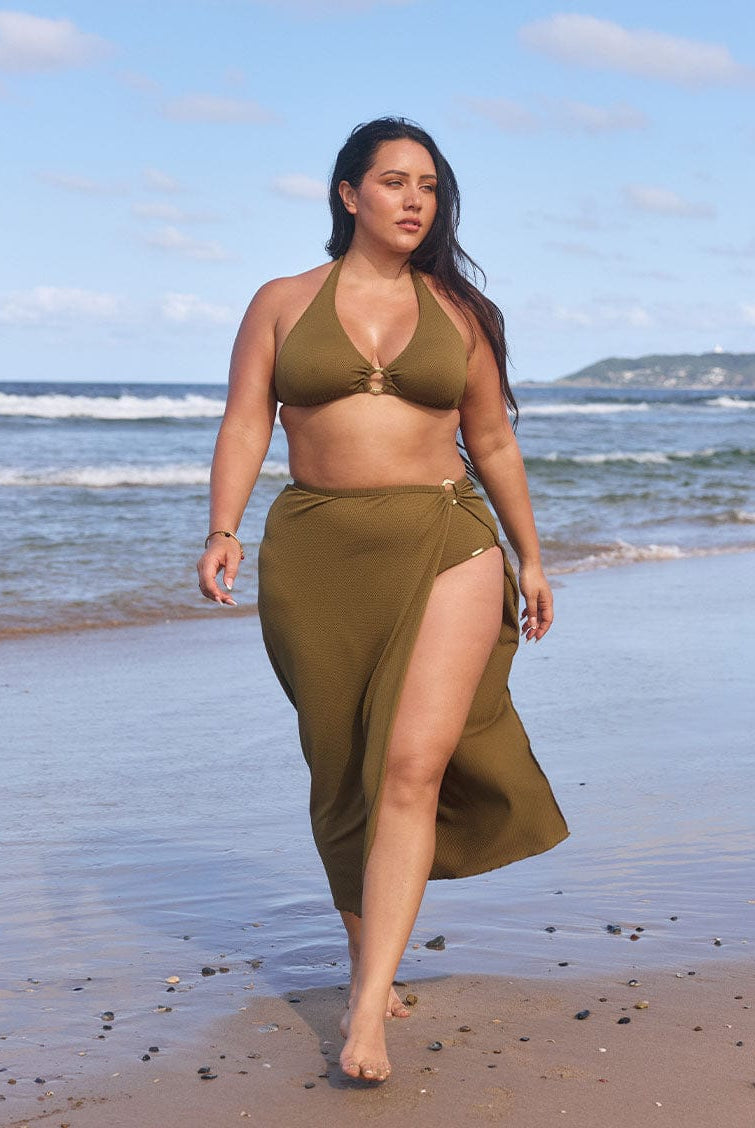 Model walks on beach wearing olive full length skirt with flattering side split
