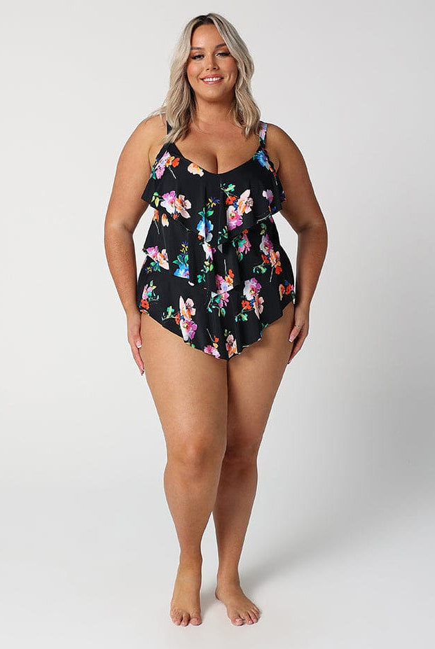 Woman wearing a black floral one-piece swimsuit on a white background