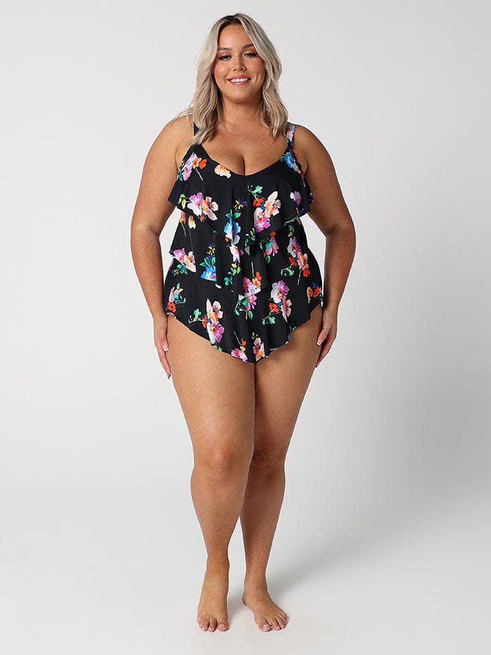 Woman wearing a black floral one-piece swimsuit on a white background