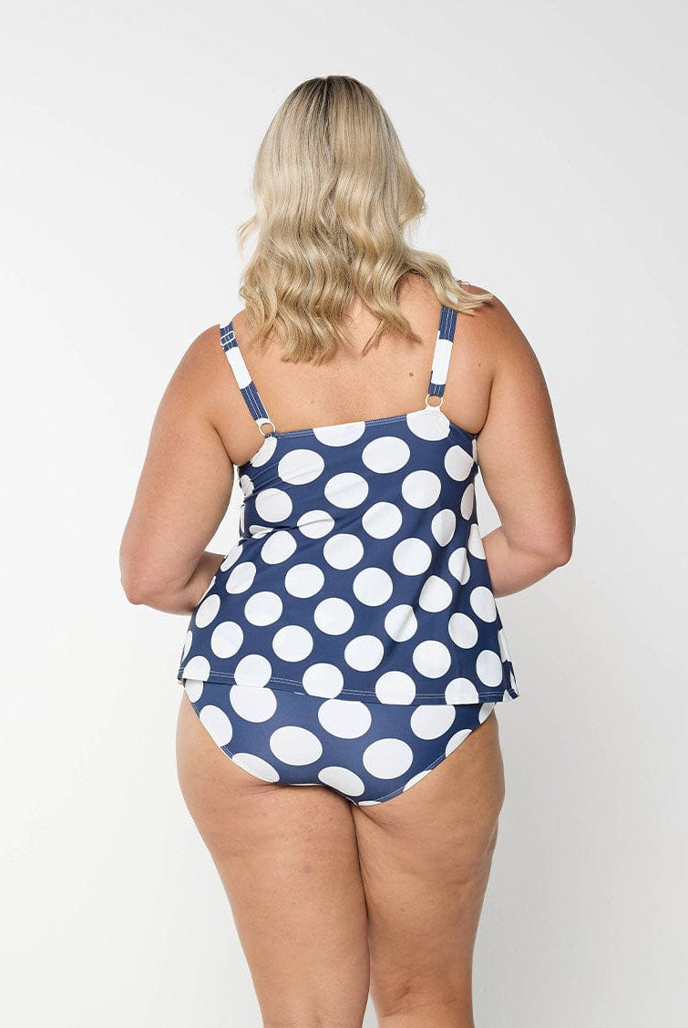 Blonde model shows back of navy and white polkadot swim pant with full coverage bottom