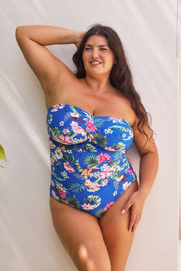 Brunette model showing flattering blue floral bandeau one piece with power mesh for tummy control and removable straps