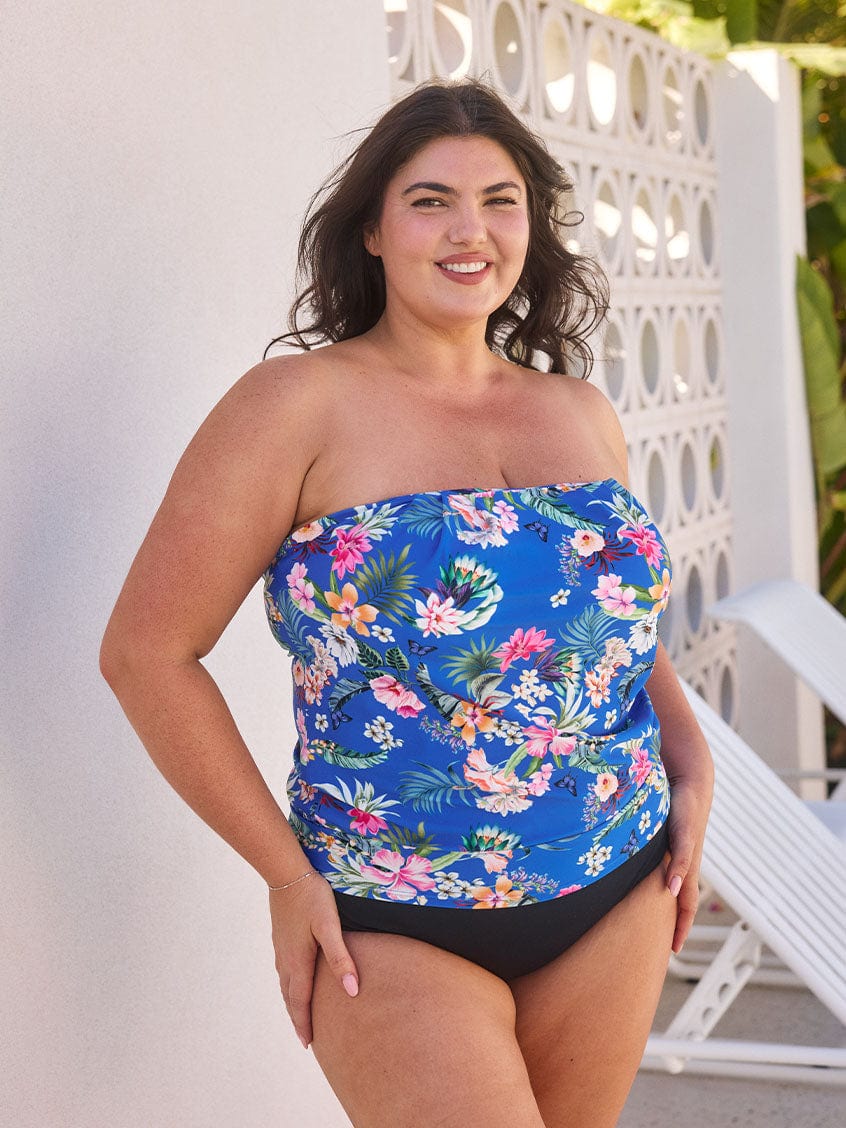 Brunette model wears bandeau tankini top with the straps removed in a vibrant blue floral print