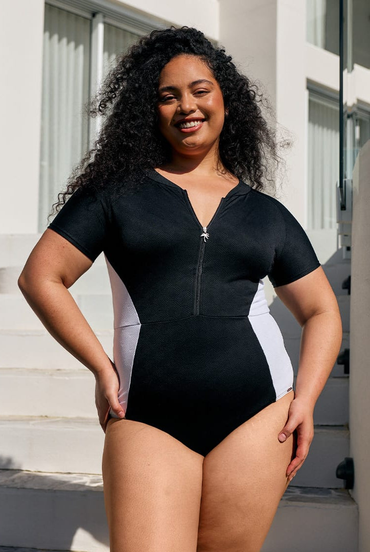 Model wearing an acapulco short sleeve one piece with zip through detail