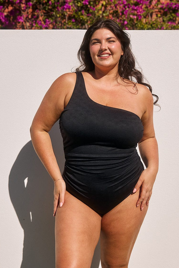 Model wearing black textured one shoulder women's swimsuit