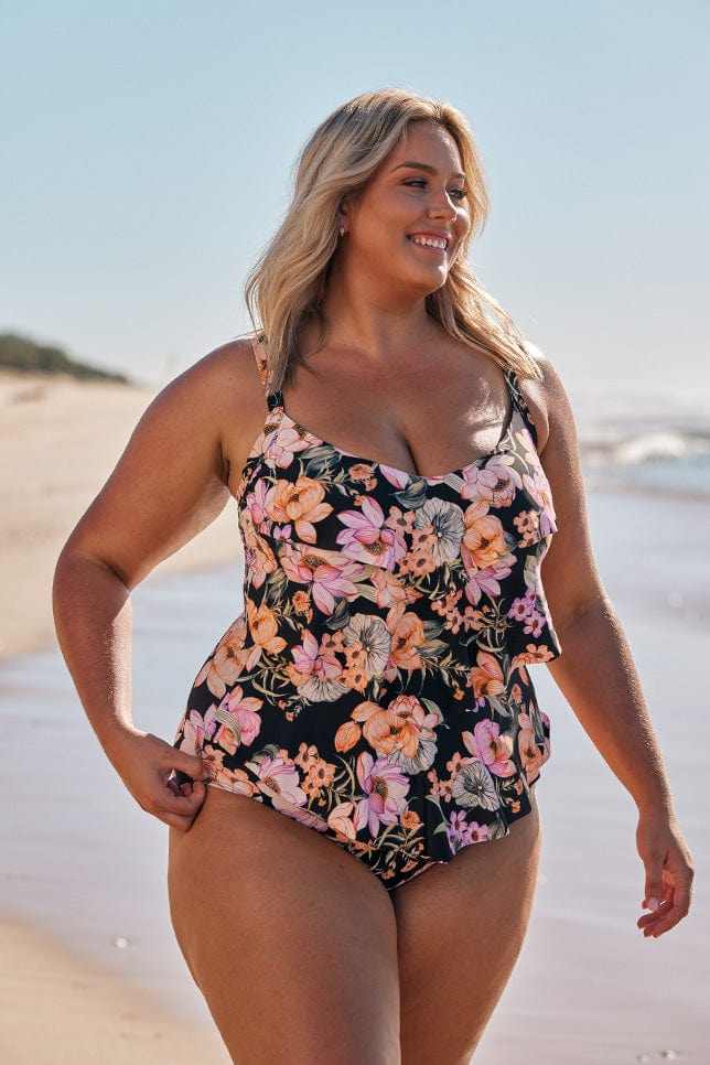 Blonde model wearing black floral 3 tier one piece at beach