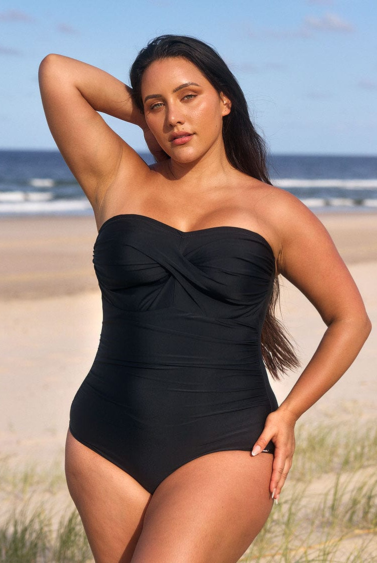 model wearing black bandeau swimsuit at beach