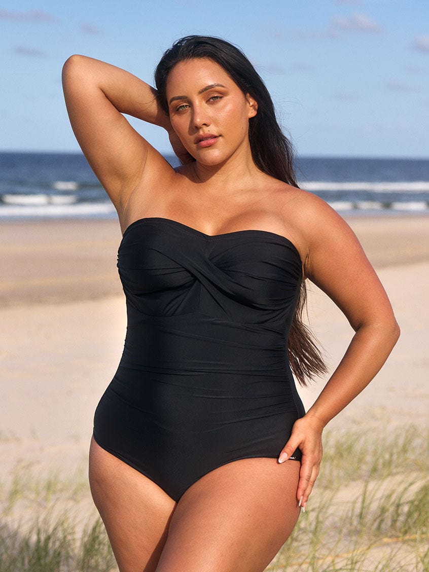 model wearing black bandeau swimsuit at beach