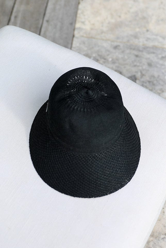 black straw wide brim beach hat laying on a white seat by the pool