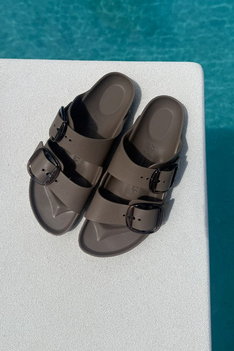 Brown sandals with black buckles on a diving board over pool