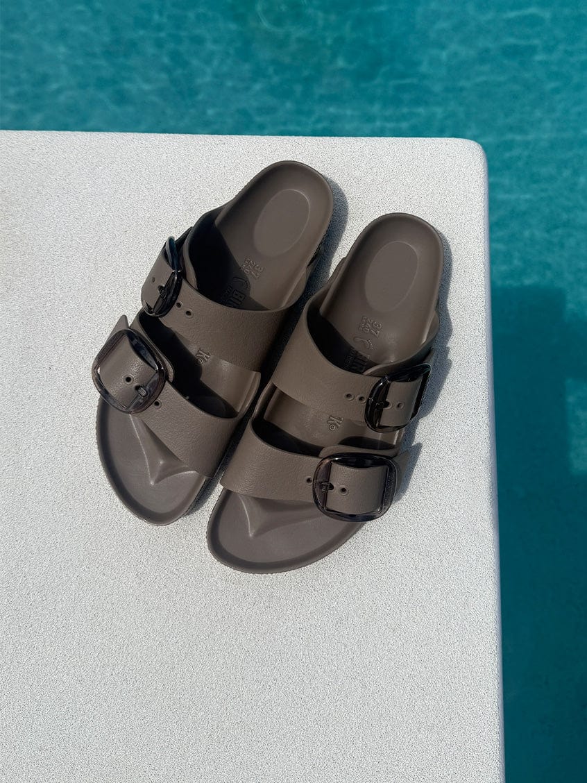 Brown sandals with black buckles on a diving board over pool