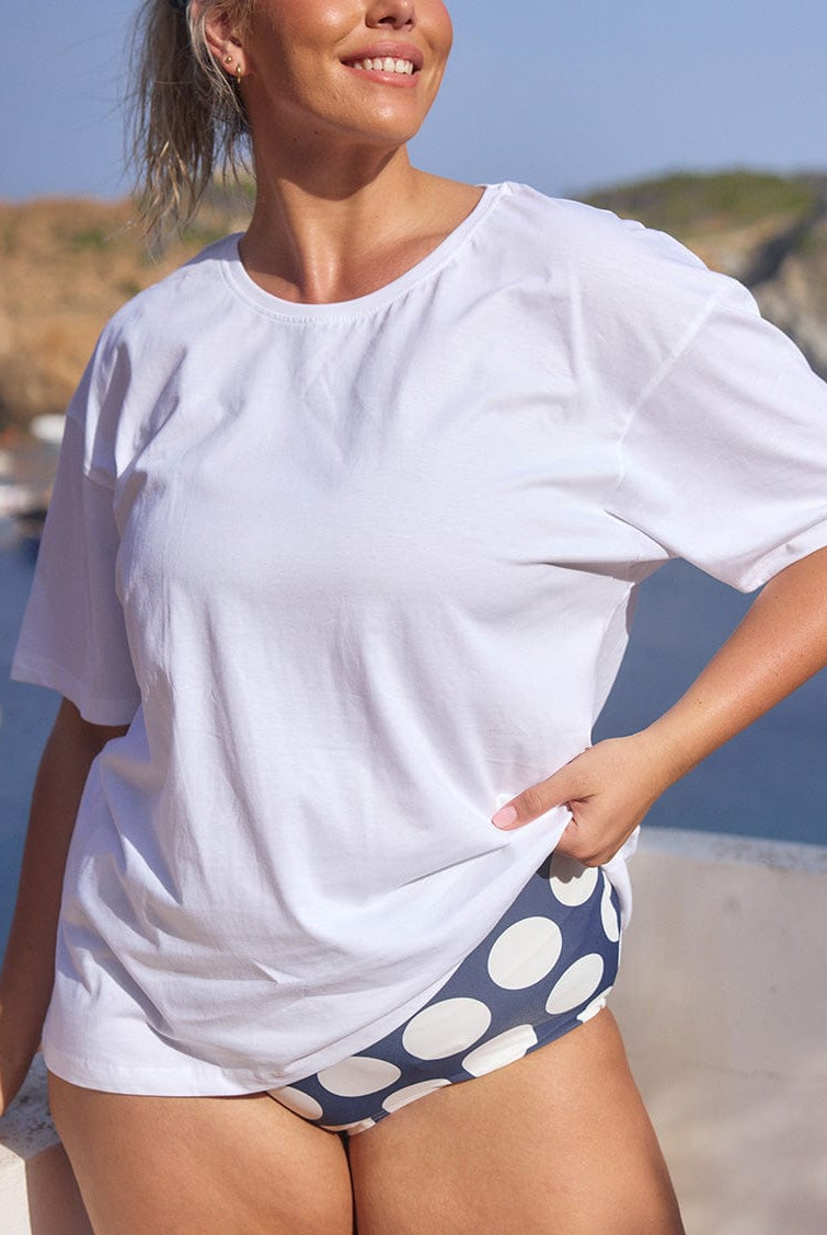 Blonde model wearing a loose white t shirt with graphics on back
