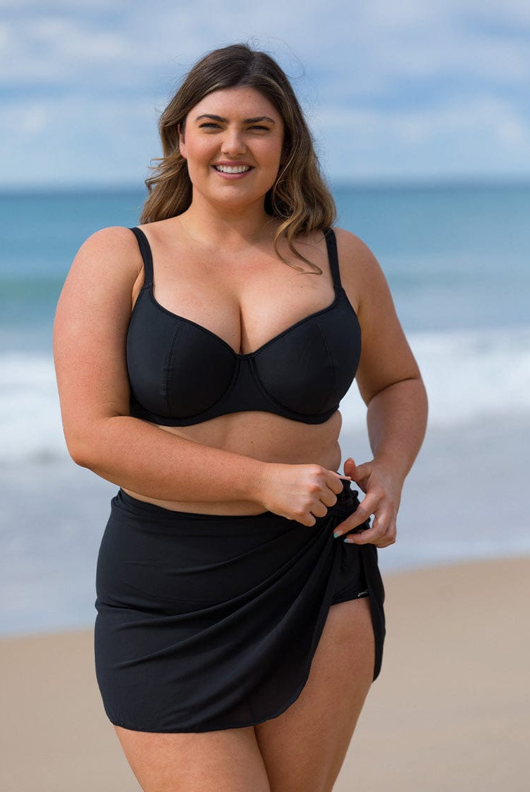 model wearing black mesh skirt with black bikini on beach