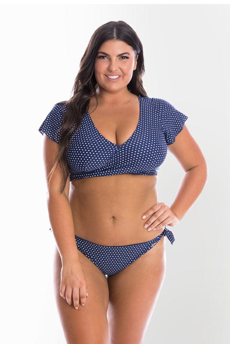 model wearing navy polka dot side tie bikini bottom and wrap top
