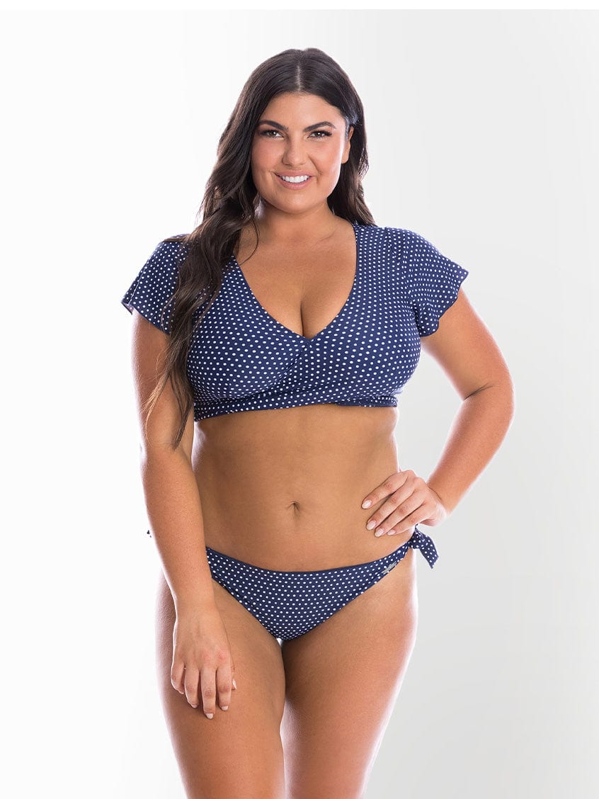 model wearing navy polka dot side tie bikini bottom and wrap top