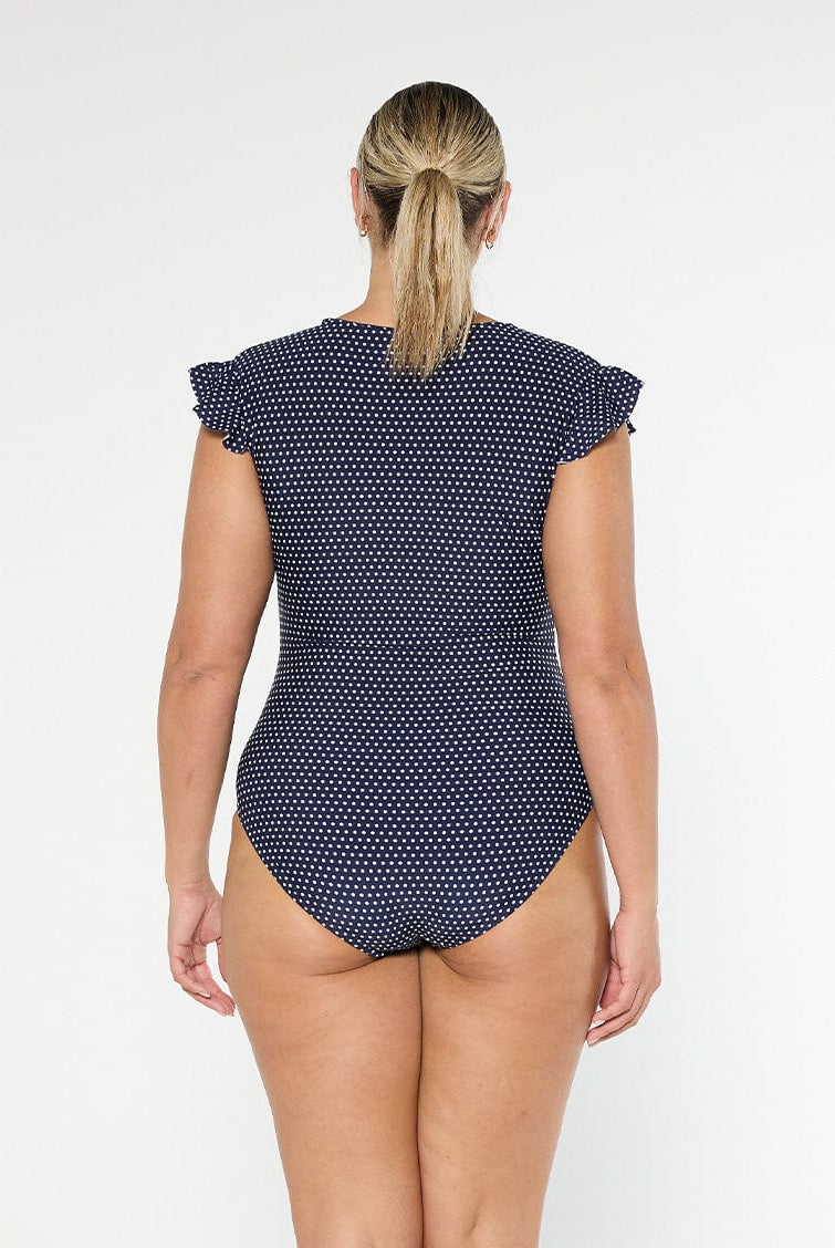 model showing full coverage back of navy polka dot frill sleeve swimsuit