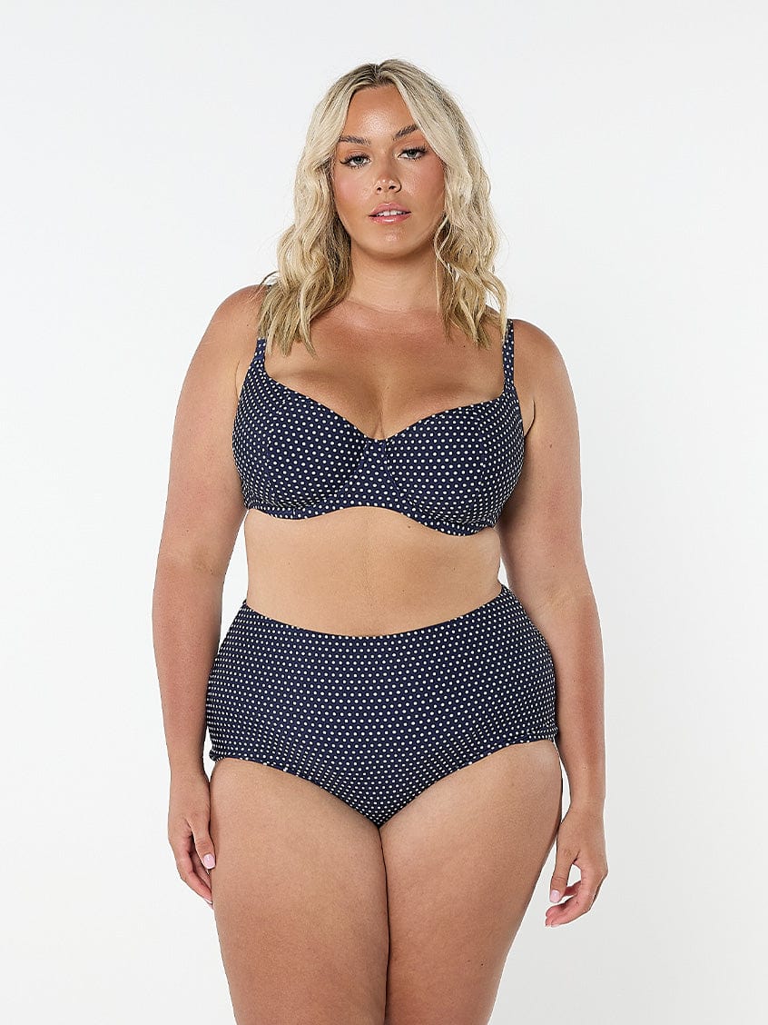 model wearing navy and white dots high waisted bikini bottoms