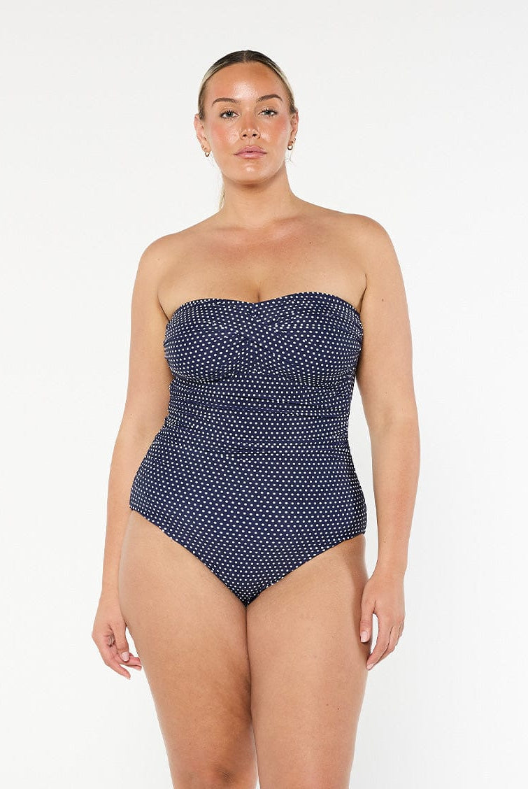 model wearing navy and white dots strapless one piece