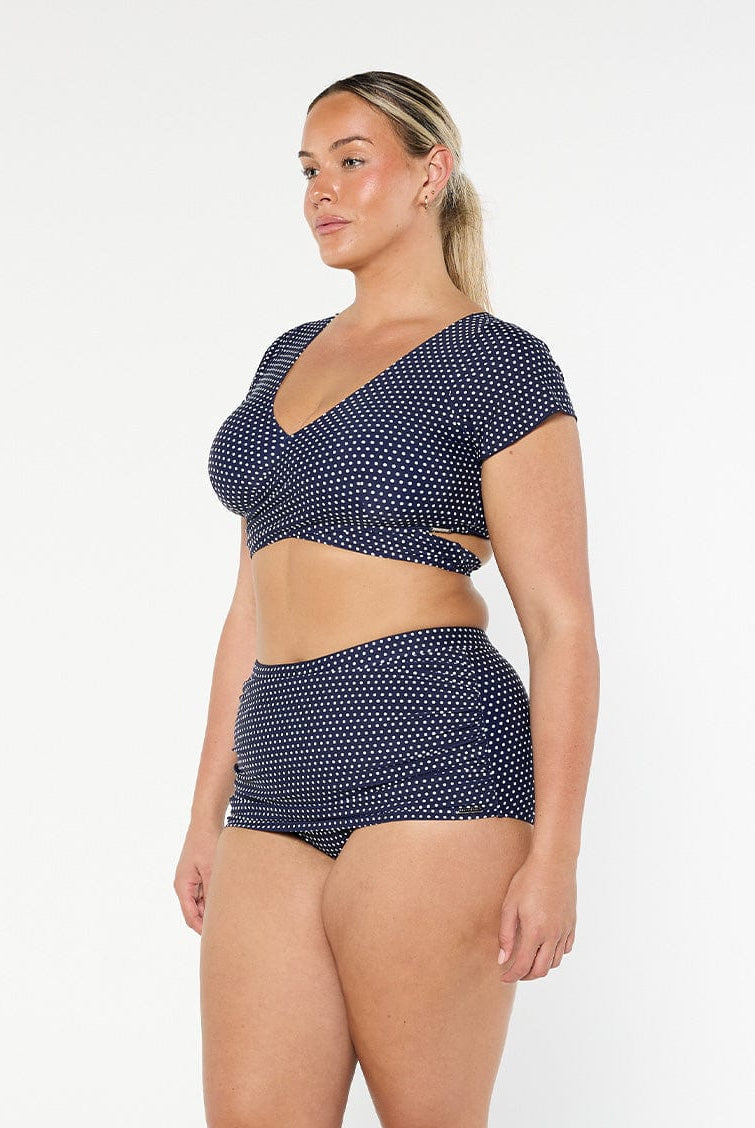 model showing side of navy polka dot wrap bikini top