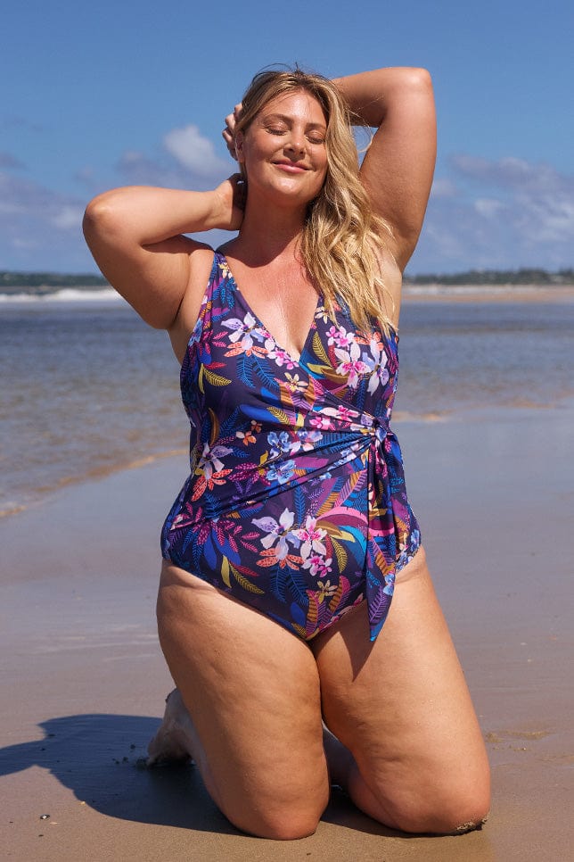 model wearing navy tropical print waist tie swimsuit at beach