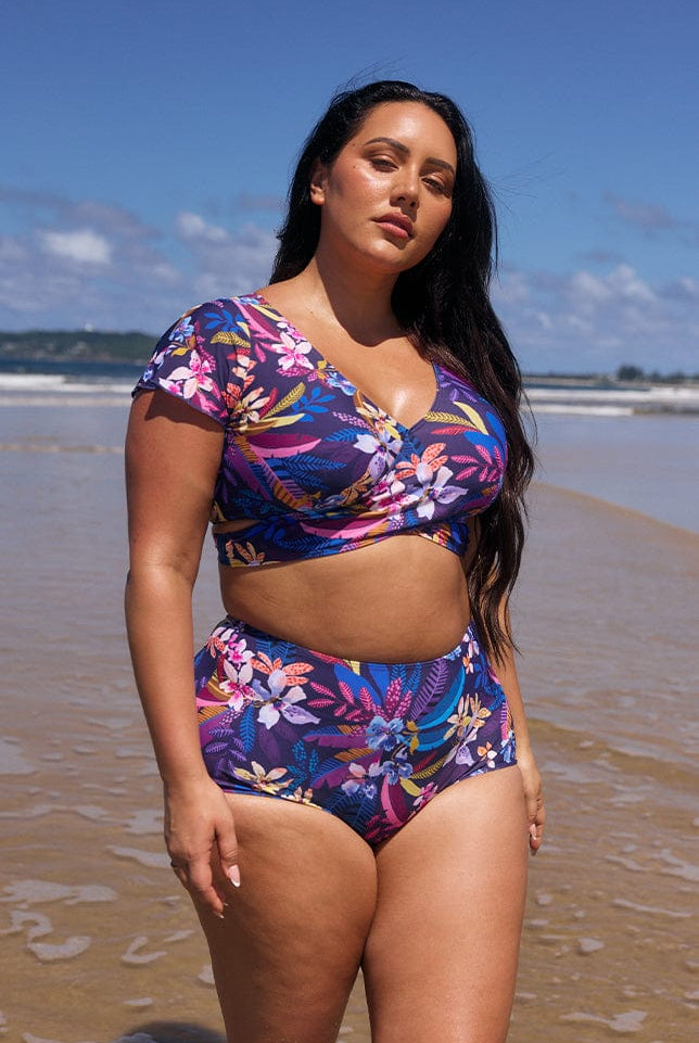model wearing navy floral wrap bikini top and matching pant on beach