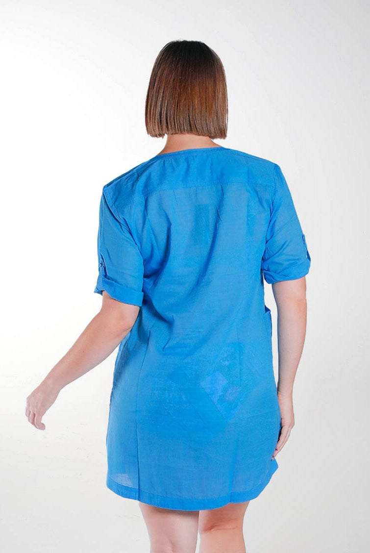 Back of model in studio wearing blue shirt dress with roll up sleeves