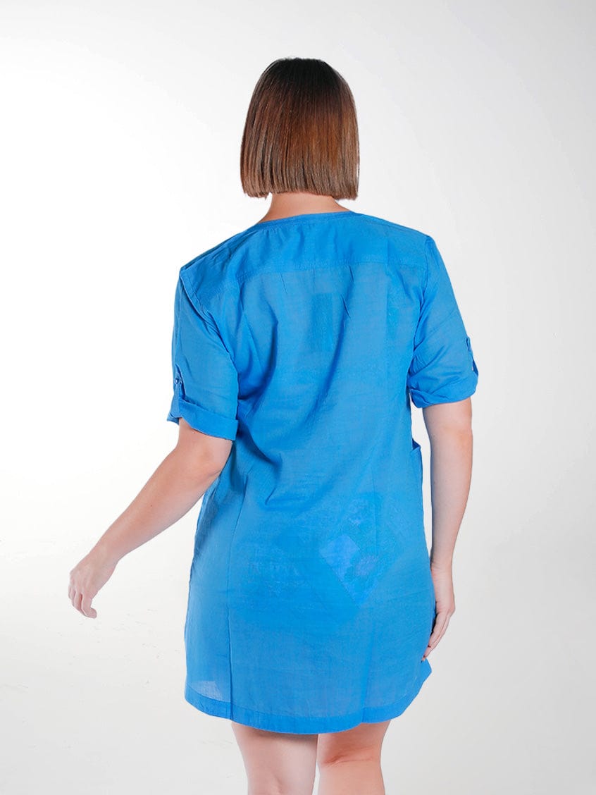 Back of model in studio wearing blue shirt dress with roll up sleeves