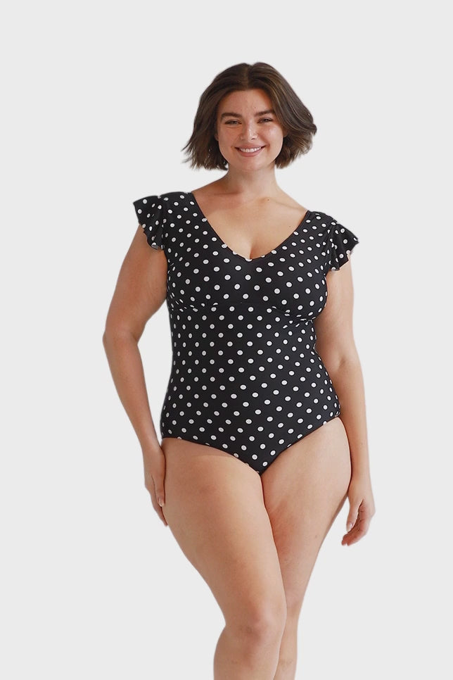 Brunette model wearing black and white dots v neck one piece