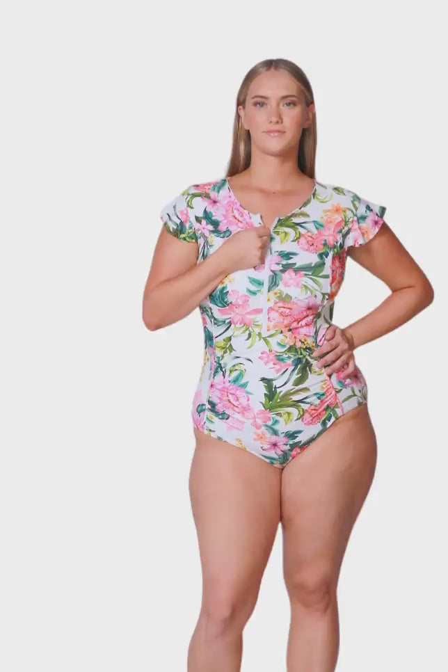 blonde plus size model wearing white based floral one piece with zip front and frill sleeves