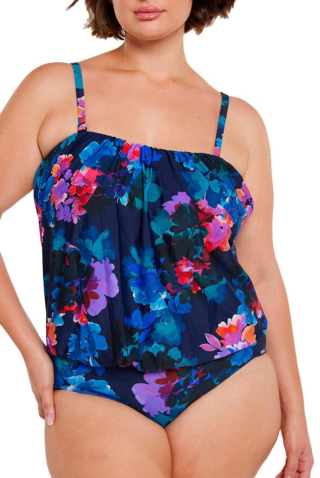 brunette women wears flattering navy blue floral flouncy one piece with removable straps