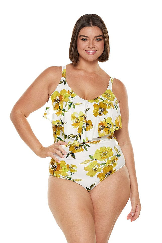 Brunette model wears flattering yellow floral one piece with frill detail and stomach ruching