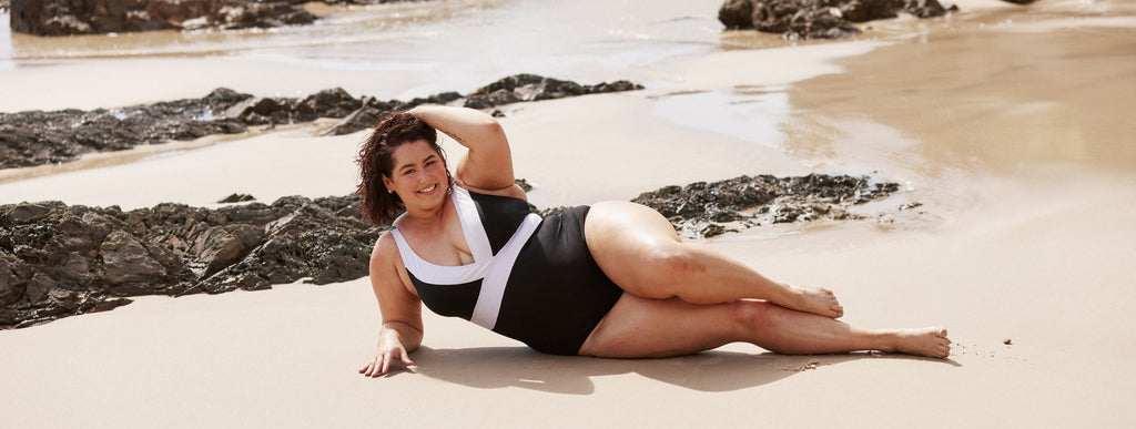 Woman with short brown hair wears black and white v neck swimsuit
