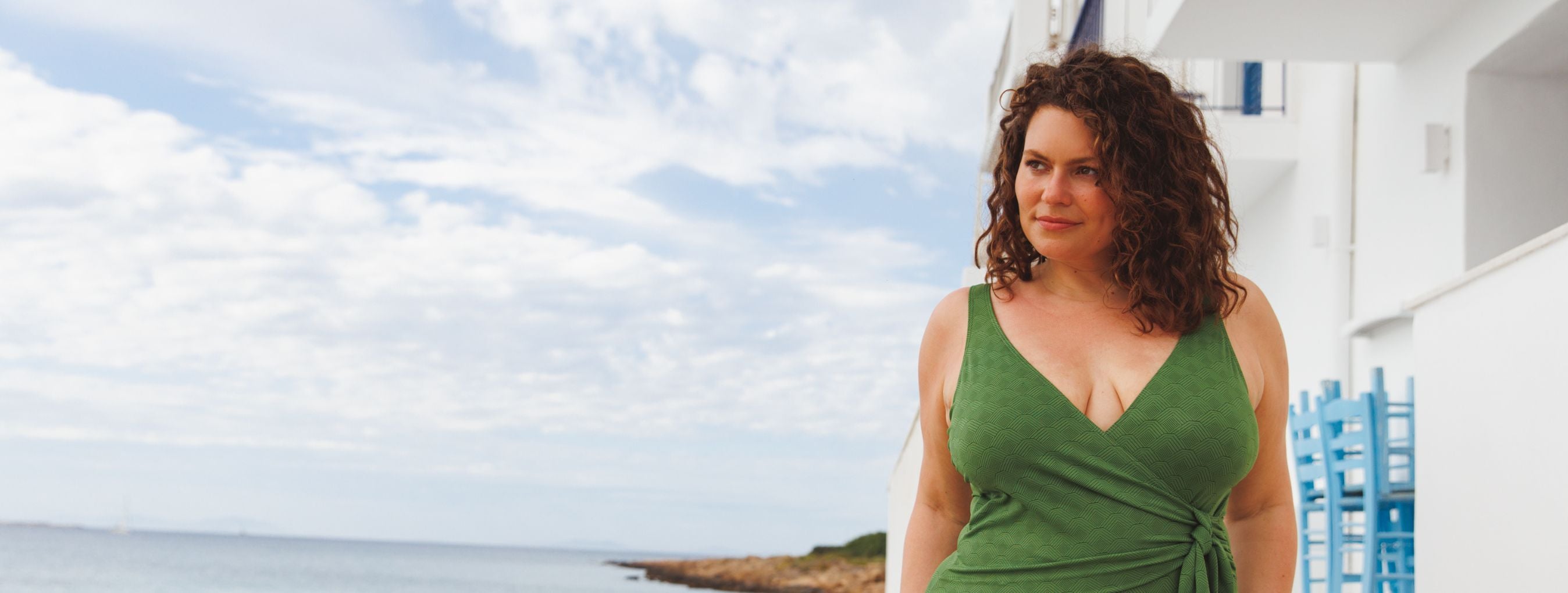 Woman with curly brown hair wears Acapulco Fresh green wrap one piece swimsuit