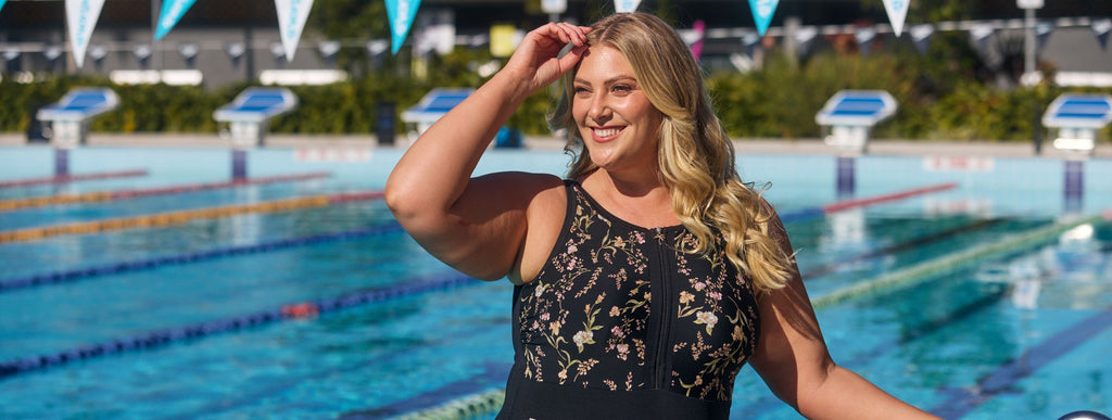 Woman with long blonde hair wears black high neck zip up one piece with floral design