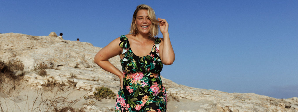 Woman with short blonde hair wears black and floral frill neckline swim dress