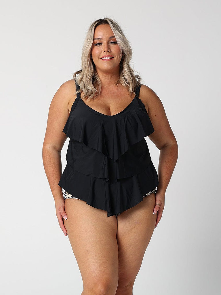 Woman wearing a black ruffled swimsuit against a white background
