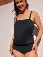 Woman wearing a black swimsuit against a neutral background