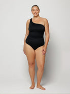 Woman wearing a black one-shoulder swimsuit on a white background