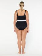 Woman wearing a black swimsuit with white trim on a white background