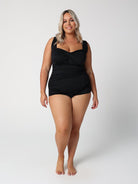 Woman wearing a black swimsuit against a white background