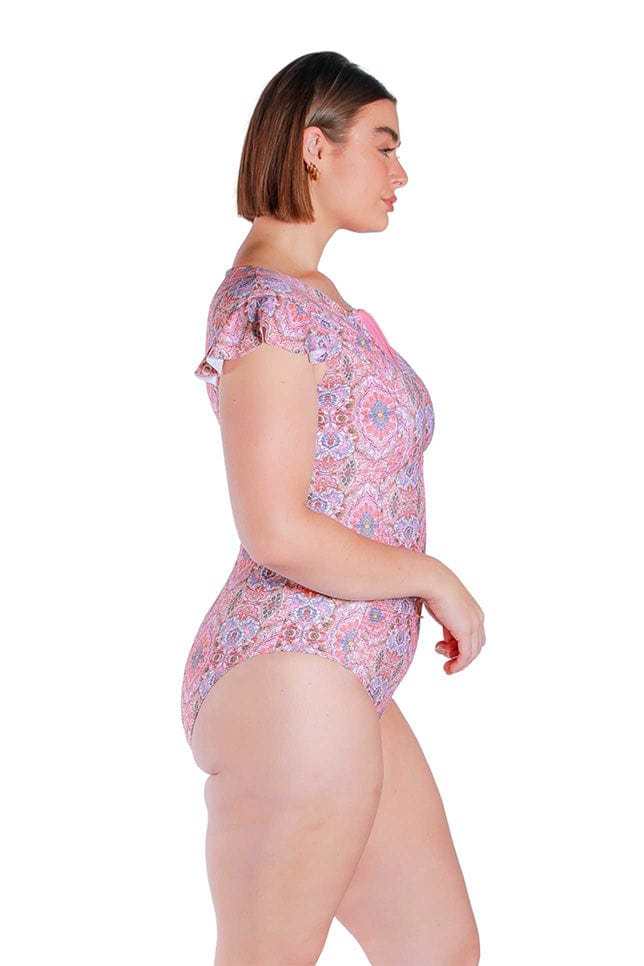 Side Shot of model wearing pink and red toned frilled sleeve one piece with zip front 